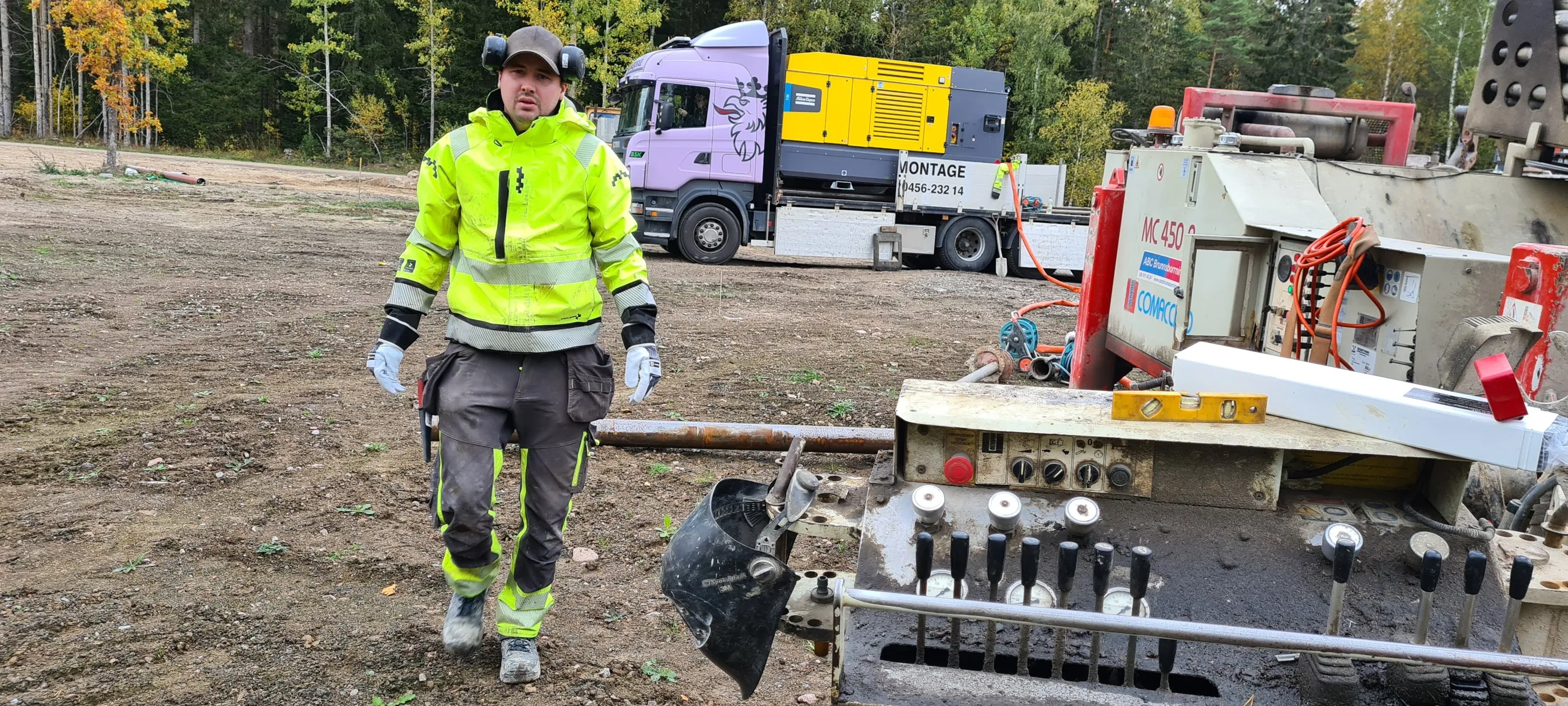 Borrare i varselkläder framför lastbil och borrigg